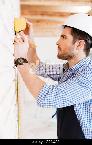 Close-up portrait of a builder measuring something with yellow type indoors Stock Photo