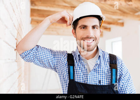 Smiling handsome builder standing near the wall in a new building Stock Photo
