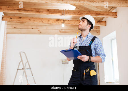Young pensive specialist builder examines his working space Stock Photo