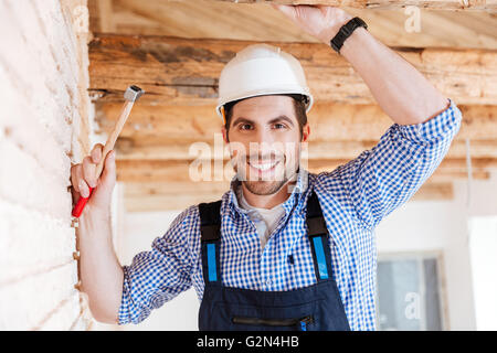 Close-up portrait of cheerful smiling builder using hammer indoors Stock Photo