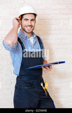 Smiling young lead worker taking notes on his clipboard while working Stock Photo