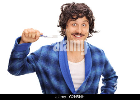 Young joyful man in a blue bathrobe holding a toothbrush isolated on white background Stock Photo