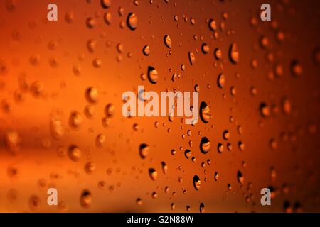 Raindrops on a window with sunset Stock Photo