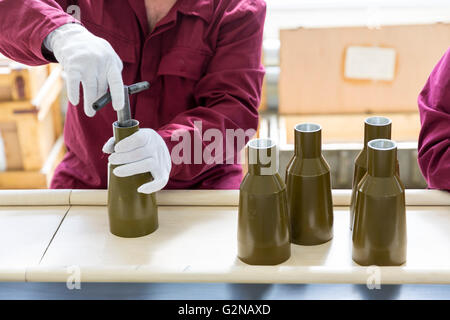 Worker is tighttening the explosive elemesnt of anti tank rocket-propelled grenades (RPG, bazooka) at an assembly line in a muni Stock Photo