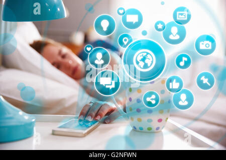 Conceptual Image Of Woman In Bed Using Social Media On Phone Stock Photo