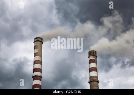Smoking big industrial chimneys in dark clouds. Concept for environmental protection Stock Photo