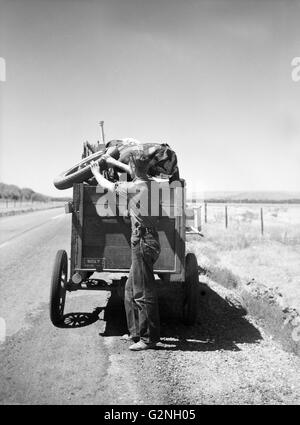 Drought Refugee from South Dakota on Highway Making Sure Nothing Falls off Trailer,Montana,USA,Arthur Rothstein for Farm Security Administration (FSA),July 1936 Stock Photo