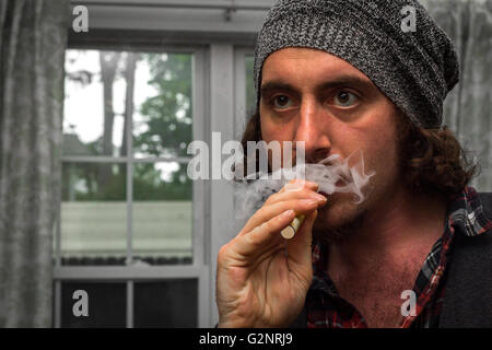 Long haired bearded man smokes a vape e-cigarette Stock Photo