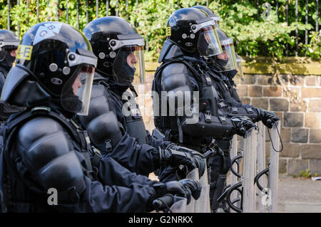 PSNI police officers in riot gear, including helmets and shields, line up across a road to block it from a crowd. Stock Photo