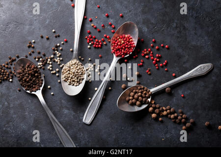 Colorful peppercorn. Red, white and black pepper spices in spoons on stone table. Top view Stock Photo