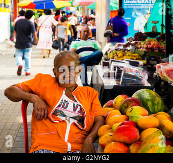 A street vendor selling fresh fruits, sits in her chair Stock Photo