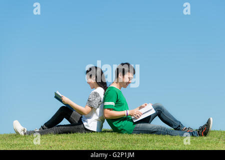 Asian couple student reading book together at outdoors park in university Stock Photo