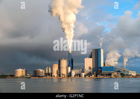 Smoking chimney at sunset on industrial buildings complex.