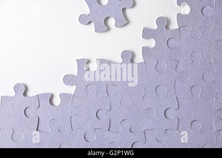 Purple unfinished puzzle on a white table. Horizontal composition. Top view Stock Photo