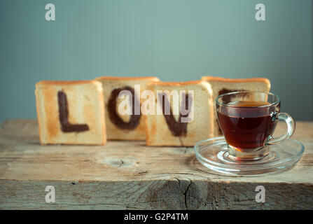 Toast Bread with the Word LOVE painted with hazelnut chocolate spread and a cup of tea Stock Photo