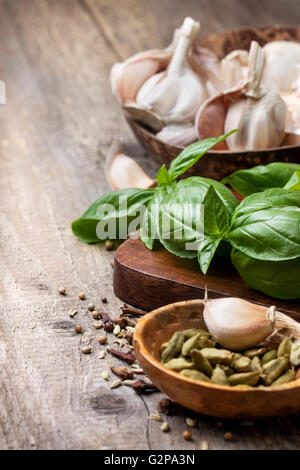 basil, garlic, spices: cardamom, cloves, black pepper on old wooden background Stock Photo