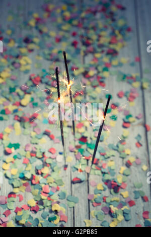 Burning Sparklers with colorful Confetti on wooden Table at a Party Stock Photo