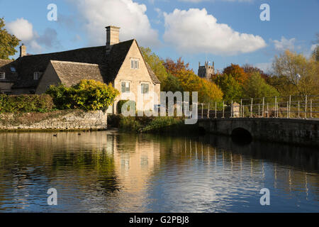 Cottage and church on the River Coln in autumn, Fairford, Cotswolds, Gloucestershire, England, United Kingdom, Europe