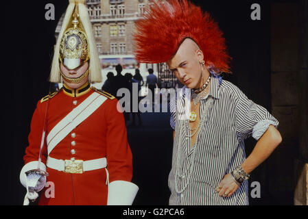 Punk rocker Matt Belgrano, 'the gentleman punk' stands with a member of the Household Cavalry, Horse Guards Parade, London, England, UK, Circa 1980's Stock Photo