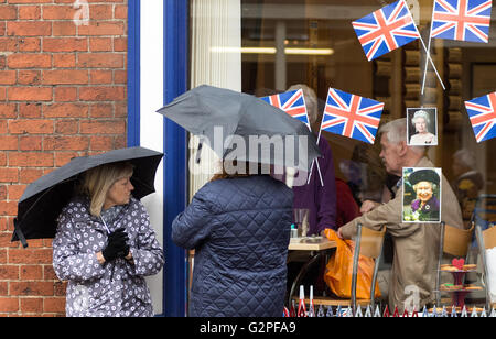 Melton Mowbray  June 1st 2016; Wet day in market town known for its pork pies, umbrella used to protect from rain fall as friends chat as the weather Forecast  is wet and windy. Credit: Clifford Norton/Alamy Live News Stock Photo