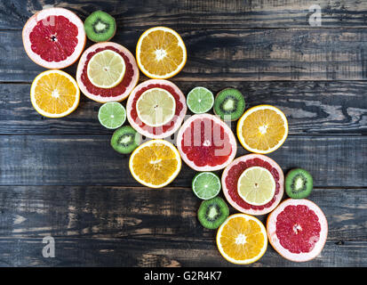 Creative arrangement of slices of citrus fruits on dark rustic wooden table. Top view with copy space. Stock Photo