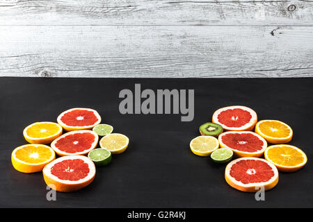 Creative arrangement of slices of citrus fruits on black painted table with copy space. Stock Photo