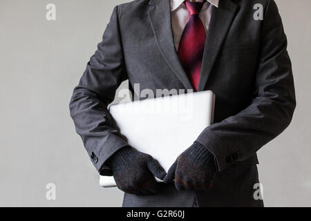 Man in suit is stealing a laptop - data or information, computer stealing concept Stock Photo