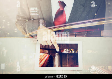 Double Exposure of Businessman touching a tablet in long exposure city scene Stock Photo