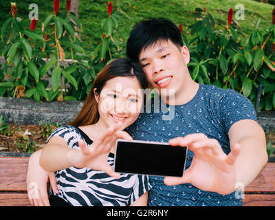 Asian couple taking a selfie photo in outdoor park scene - love and relationship concept Stock Photo