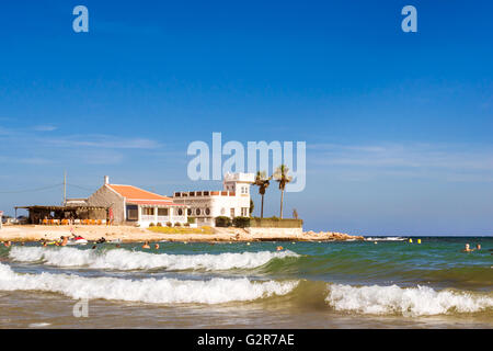 TORREVIEJA, SPAIN - SEPTEMBER 13, 2014: Sunny Mediterranean beach, Tourists relax on wave. People bathe in crystal clear water Stock Photo