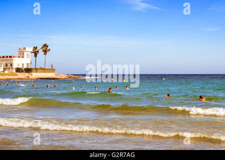TORREVIEJA, SPAIN - SEPTEMBER 13, 2014: Sunny Mediterranean beach, Tourists relax on wave. People bathe in crystal clear water Stock Photo