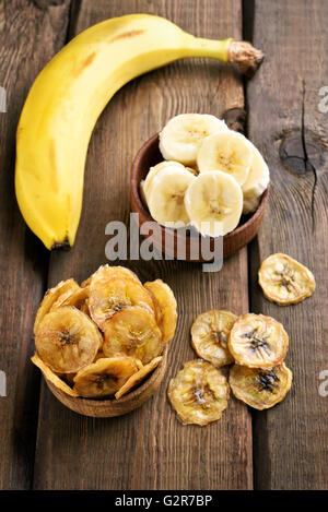 Banana chips and fresh fruits on wooden background, top view Stock Photo