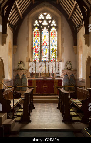 Inside view of Holy Trinity Church, an English village church, looking up the nave towards the altar with a stained glass window