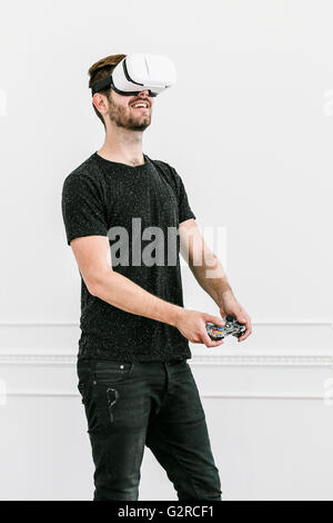 A Close up of a man with a virtual reality headset against a plain white background using a game controller Stock Photo