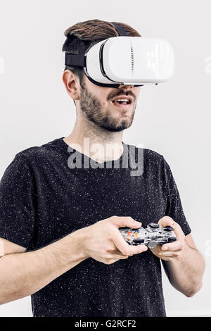 A Close up of a man with a virtual reality headset against a plain white background using a game controller Stock Photo