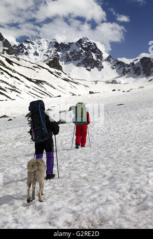 Dog and two hikers in snowy mountains. Turkey, Kachkar Mountains (highest part of Pontic Mountains). Stock Photo