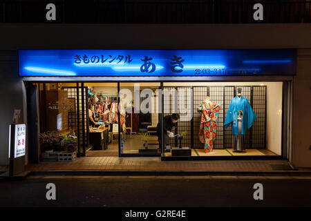 A woman waters a plant in the shop window of a Kimono shop in Dogenzaka, Shibuya, Tokyo, Japan. Stock Photo