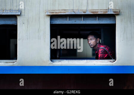 A young man waiting for the train to leave the station, Central Railway Station, Yangon, Myanmar. Stock Photo