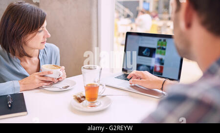 Tight shot of woman looking at laptop over mans shoulder Stock Photo