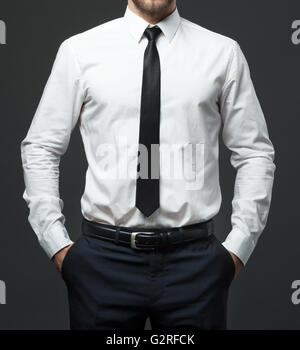 Midsection of fit young businessman standing in formal white shirt, black tie and pants. Stock Photo