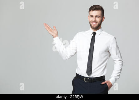 Your logo or product goes here! Studio shot of handsome young businessman holding his arm up presenting copyspace. Stock Photo