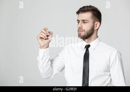 Young handsome businessman writing on a transparent pane - copyspace. Stock Photo