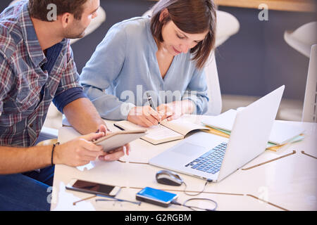 Businessman working beside his female colleague on laptop computer Stock Photo
