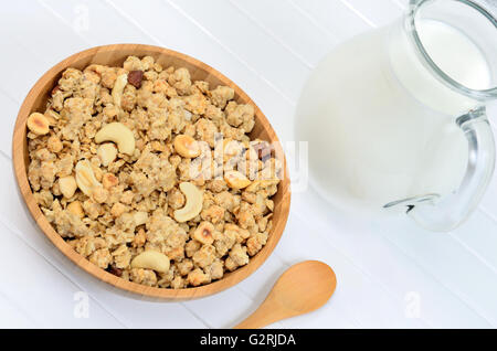 Muesli in a bamboo bowl with milk on white wooden table Stock Photo