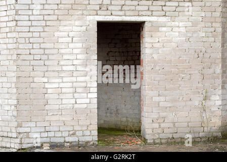 white cracked brick wall with a doorway Stock Photo