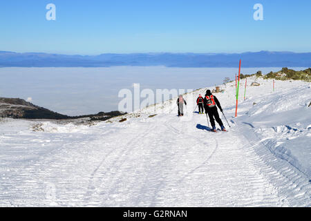 Three skiers descend from the peak Stock Photo