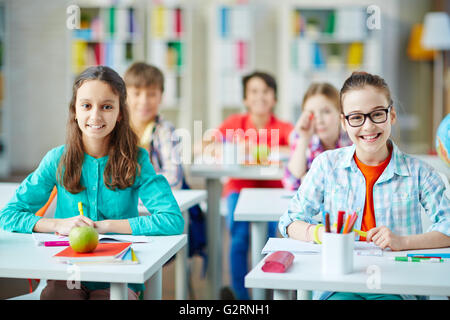 Schoolgirls sitting by desks at lesson Stock Photo