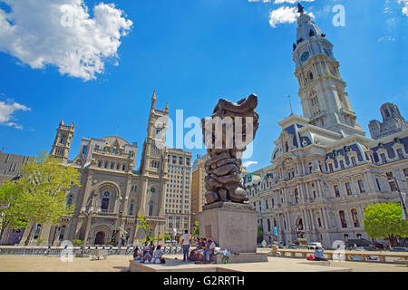 Philadelphia, USA - May 4, 2015: Square with Government of the people sculpture and tourists, and Philadelphia City Hall and Church on the background. Pennsylvania, USA. Stock Photo