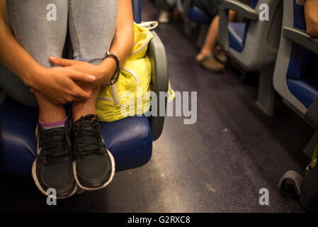 A young woman embracing her legs in the seat of a train as it moves, Italy. Stock Photo