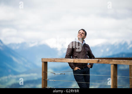 Happy carefree and free man looking to a sky with hands in his pockets over mountain alps landscape Stock Photo